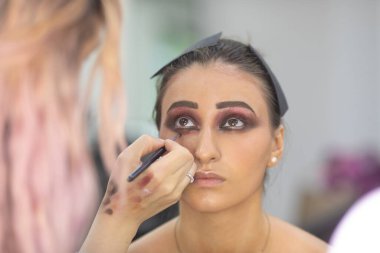 Profesyonel makyöz güzellik salonundaki güzel bayan modellere makyaj yapıyor..               