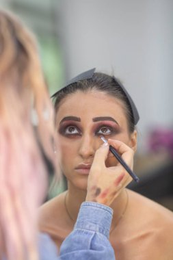 Profesyonel makyöz güzellik salonundaki güzel bayan modellere makyaj yapıyor..               