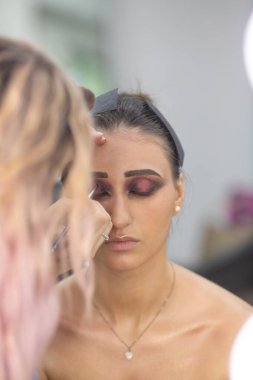 Profesyonel makyöz güzellik salonundaki güzel bayan modellere makyaj yapıyor..               
