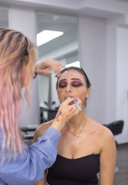 Profesyonel makyöz güzellik salonundaki güzel bayan modellere makyaj yapıyor..               