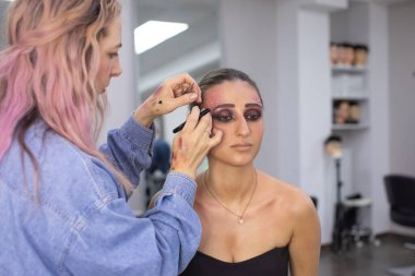 Profesyonel makyöz güzellik salonundaki güzel bayan modellere makyaj yapıyor..               