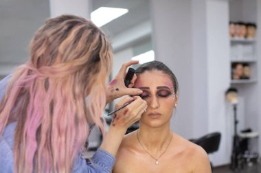 Profesyonel makyöz güzellik salonundaki güzel bayan modellere makyaj yapıyor..               
