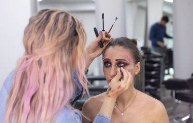 Profesyonel makyöz güzellik salonundaki güzel bayan modellere makyaj yapıyor..               