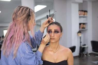 Profesyonel makyöz güzellik salonundaki güzel bayan modellere makyaj yapıyor..               
