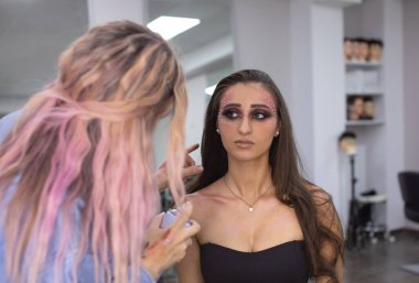 Profesyonel makyöz güzellik salonundaki güzel bayan modellere makyaj yapıyor..               