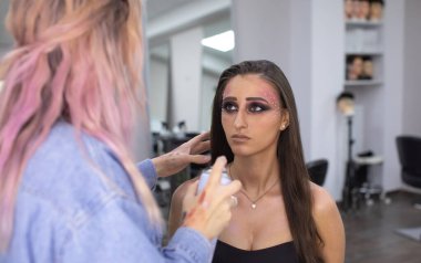 Profesyonel makyöz güzellik salonundaki güzel bayan modellere makyaj yapıyor..               