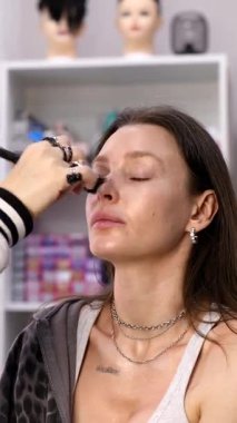 Profesyonel makyöz güzellik salonundaki güzel bayan modellere makyaj yapıyor..     