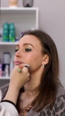 Profesyonel makyöz güzellik salonundaki güzel bayan modellere makyaj yapıyor..     