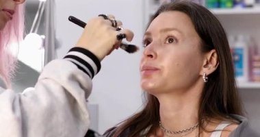 Profesyonel makyöz güzellik salonundaki güzel bayan modellere makyaj yapıyor..     