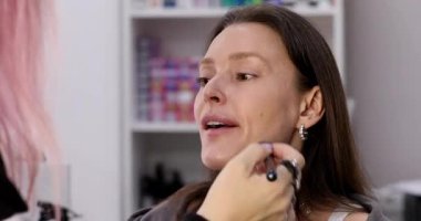 Profesyonel makyöz güzellik salonundaki güzel bayan modellere makyaj yapıyor..     