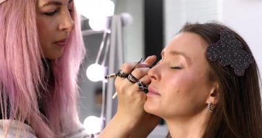 Profesyonel makyöz güzellik salonundaki güzel bayan modellere makyaj yapıyor..     