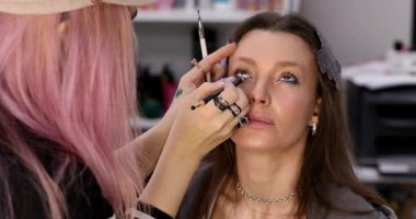 Profesyonel makyöz güzellik salonundaki güzel bayan modellere makyaj yapıyor..     