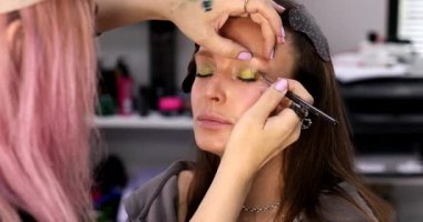 Profesyonel makyöz güzellik salonundaki güzel bayan modellere makyaj yapıyor..     