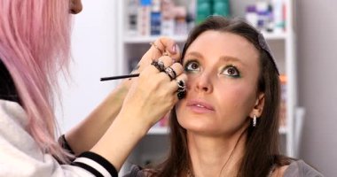 Profesyonel makyöz güzellik salonundaki güzel bayan modellere makyaj yapıyor..     