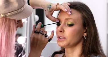 Profesyonel makyöz güzellik salonundaki güzel bayan modellere makyaj yapıyor..     