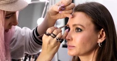 Profesyonel makyöz güzellik salonundaki güzel bayan modellere makyaj yapıyor..     