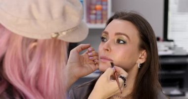 Profesyonel makyöz güzellik salonundaki güzel bayan modellere makyaj yapıyor..     