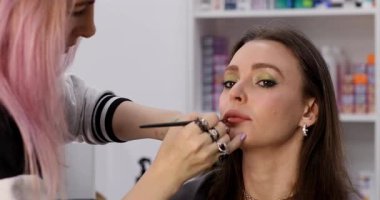 Profesyonel makyöz güzellik salonundaki güzel bayan modellere makyaj yapıyor..     