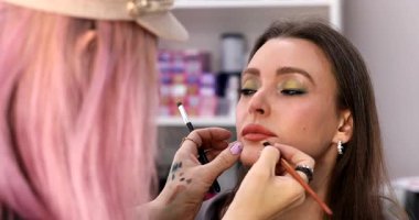 Profesyonel makyöz güzellik salonundaki güzel bayan modellere makyaj yapıyor..     