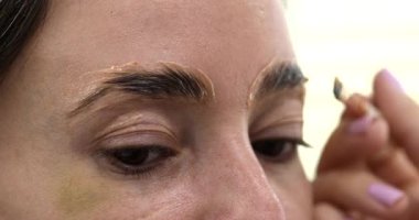 Güzellik salonunda güzel bir genç kadının portresi, kaş makyajı yaptırıyor..                          