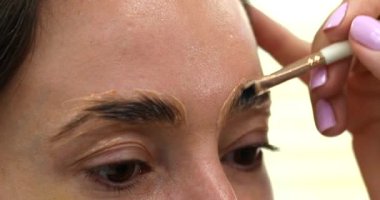 Güzellik salonunda güzel bir genç kadının portresi, kaş makyajı yaptırıyor..                          