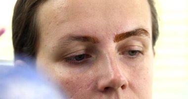 Güzellik salonunda güzel bir genç kadının portresi, kaş makyajı yaptırıyor..                          