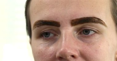 Güzellik salonunda güzel bir genç kadının portresi, kaş makyajı yaptırıyor..                          