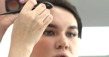 Profesyonel makyöz güzellik salonundaki güzel bayan modellere makyaj yapıyor..                   