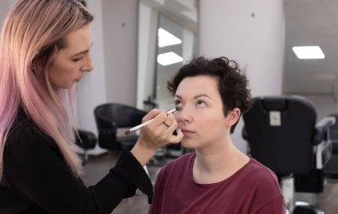 Profesyonel makyöz güzellik salonundaki güzel kadın mankene makyaj yapıyor..                      