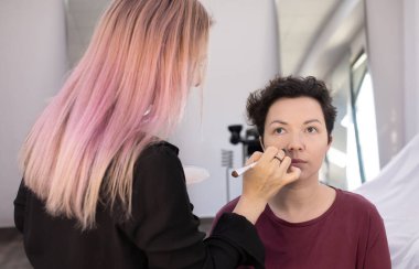 Profesyonel makyöz güzellik salonundaki güzel kadın mankene makyaj yapıyor..                      