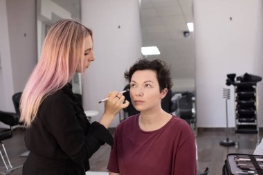 Profesyonel makyöz güzellik salonundaki güzel kadın mankene makyaj yapıyor..                      