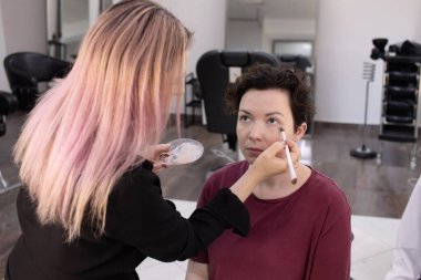 Profesyonel makyöz güzellik salonundaki güzel kadın mankene makyaj yapıyor..                      