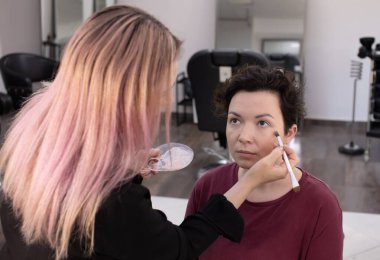 Profesyonel makyöz güzellik salonundaki güzel kadın mankene makyaj yapıyor..                      