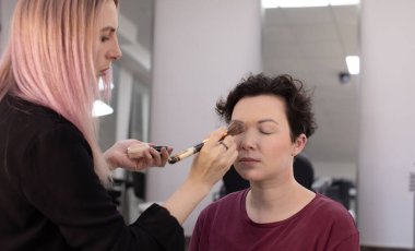 Profesyonel makyöz güzellik salonundaki güzel kadın mankene makyaj yapıyor..                      