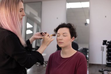 Profesyonel makyöz güzellik salonundaki güzel kadın mankene makyaj yapıyor..                      