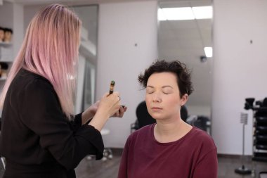 Profesyonel makyöz güzellik salonundaki güzel kadın mankene makyaj yapıyor..                      