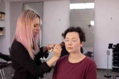 Profesyonel makyöz güzellik salonundaki güzel kadın mankene makyaj yapıyor..                      