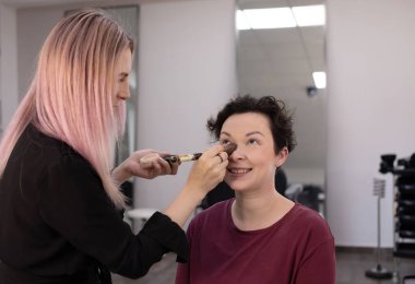 Profesyonel makyöz güzellik salonundaki güzel kadın mankene makyaj yapıyor..                      