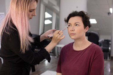 Profesyonel makyöz güzellik salonundaki güzel kadın mankene makyaj yapıyor..                      