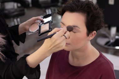 Profesyonel makyöz güzellik salonundaki güzel kadın mankene makyaj yapıyor..                      