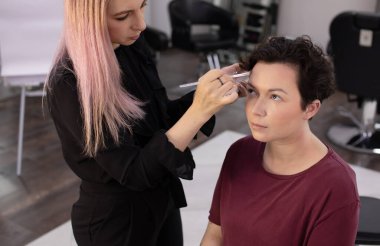 Profesyonel makyöz güzellik salonundaki güzel kadın mankene makyaj yapıyor..                      