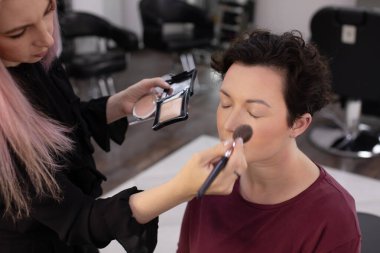 Profesyonel makyöz güzellik salonundaki güzel kadın mankene makyaj yapıyor..                      