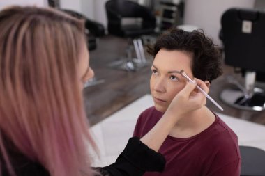 Profesyonel makyöz güzellik salonundaki güzel kadın mankene makyaj yapıyor..                      