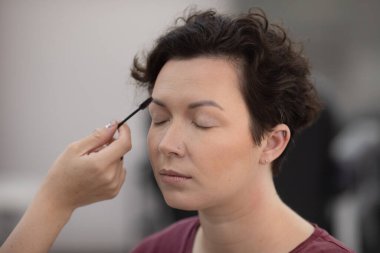 Profesyonel makyöz güzellik salonundaki güzel kadın mankene makyaj yapıyor..                      