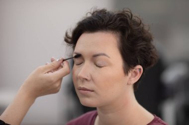 Profesyonel makyöz güzellik salonundaki güzel kadın mankene makyaj yapıyor..                      