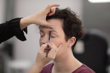 Profesyonel makyöz güzellik salonundaki güzel kadın mankene makyaj yapıyor..                      