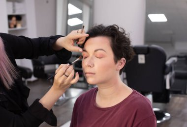 Profesyonel makyöz güzellik salonundaki güzel kadın mankene makyaj yapıyor..                      