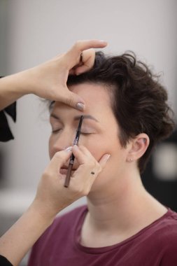 Profesyonel makyöz güzellik salonundaki güzel kadın mankene makyaj yapıyor..                      