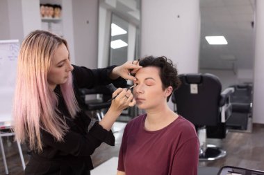 Profesyonel makyöz güzellik salonundaki güzel kadın mankene makyaj yapıyor..                      