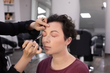 Profesyonel makyöz güzellik salonundaki güzel kadın mankene makyaj yapıyor..                      